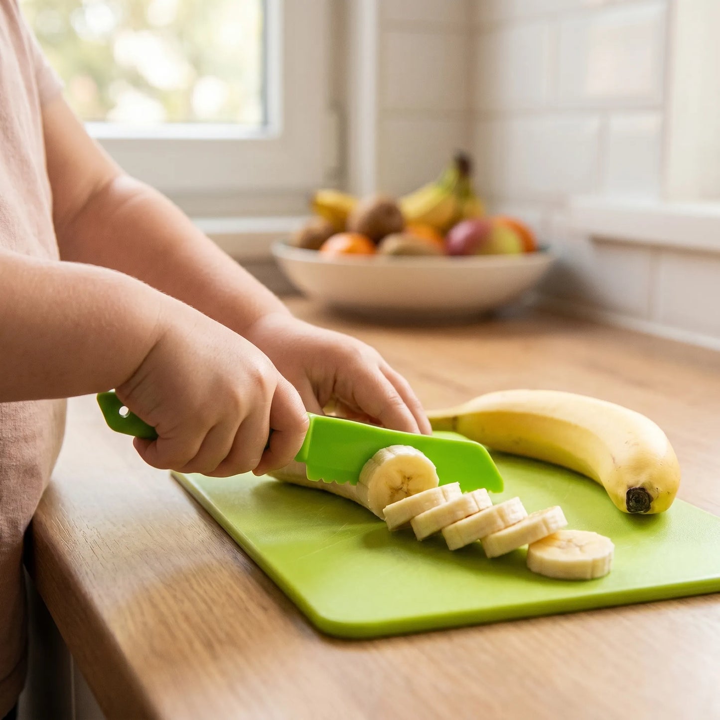 Kind schneidet sicher eine Banane mit dem grünen MiniKochBar Kunststoffmesser